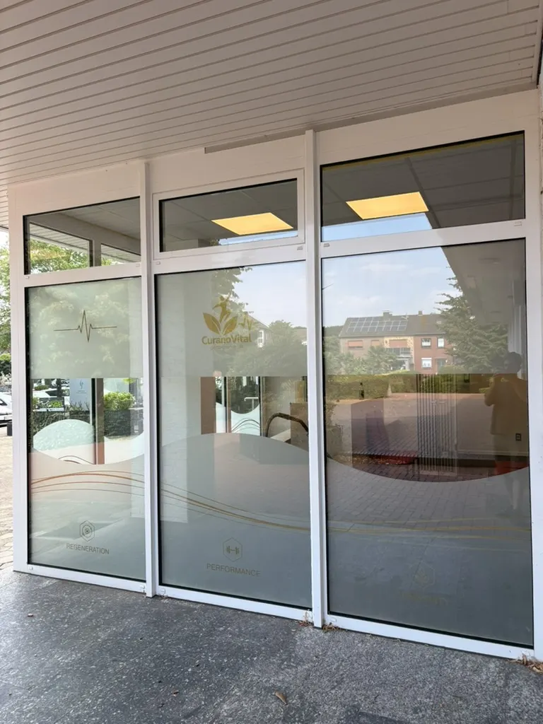 Außenansicht der CuranoVital-Glasfront mit Logo und Sichtschutzfolie mit Wellenkante