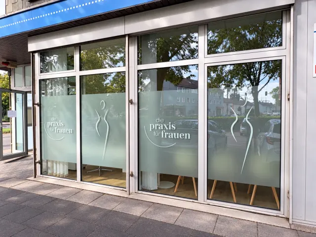 Glasfront der Praxis für Frauen mit Sichtschutzfolie, Praxislogo und Körpersilhouette auf vier Fensterfeldern